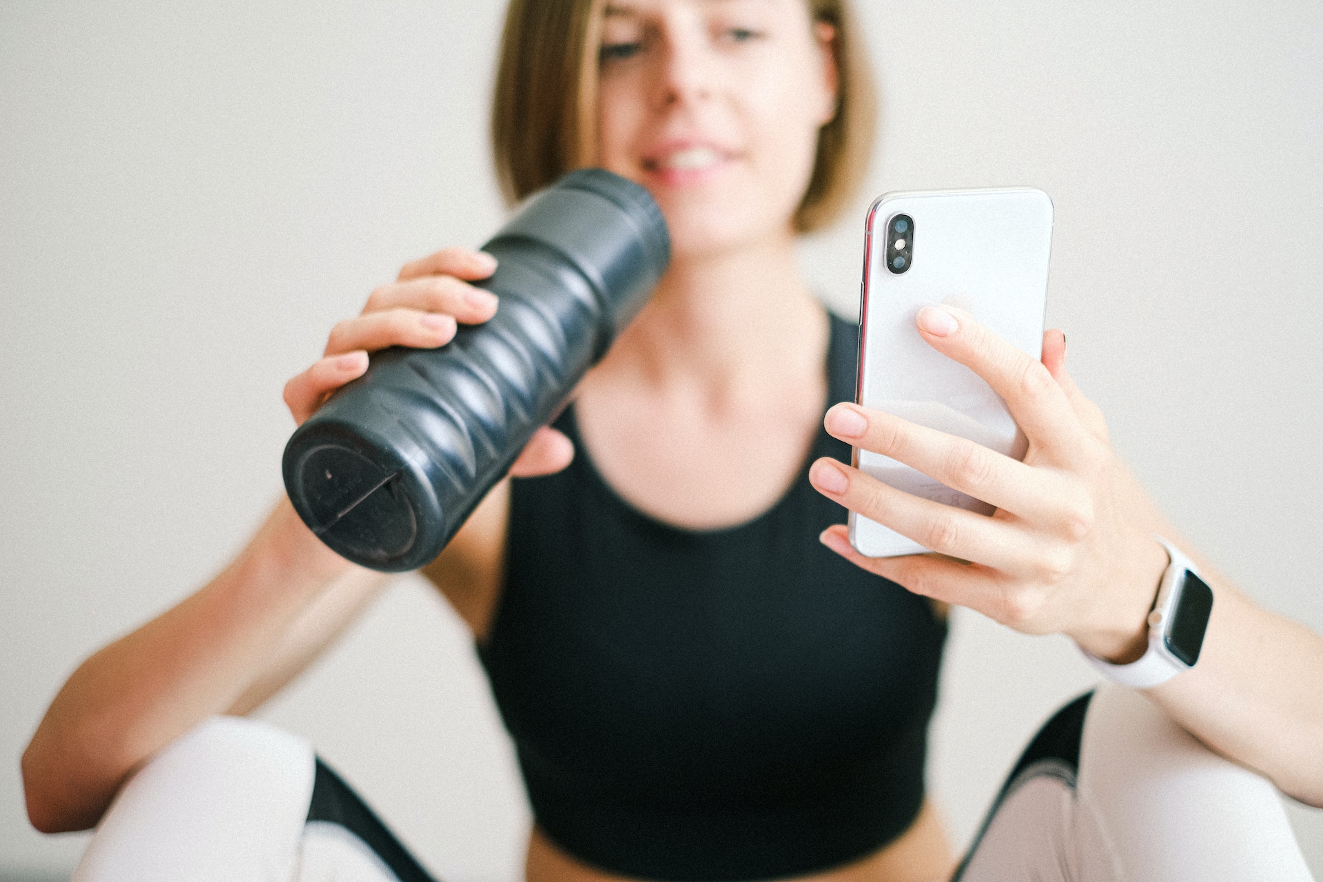 nutrición deportiva, chica bebiendo de botella con el móvil