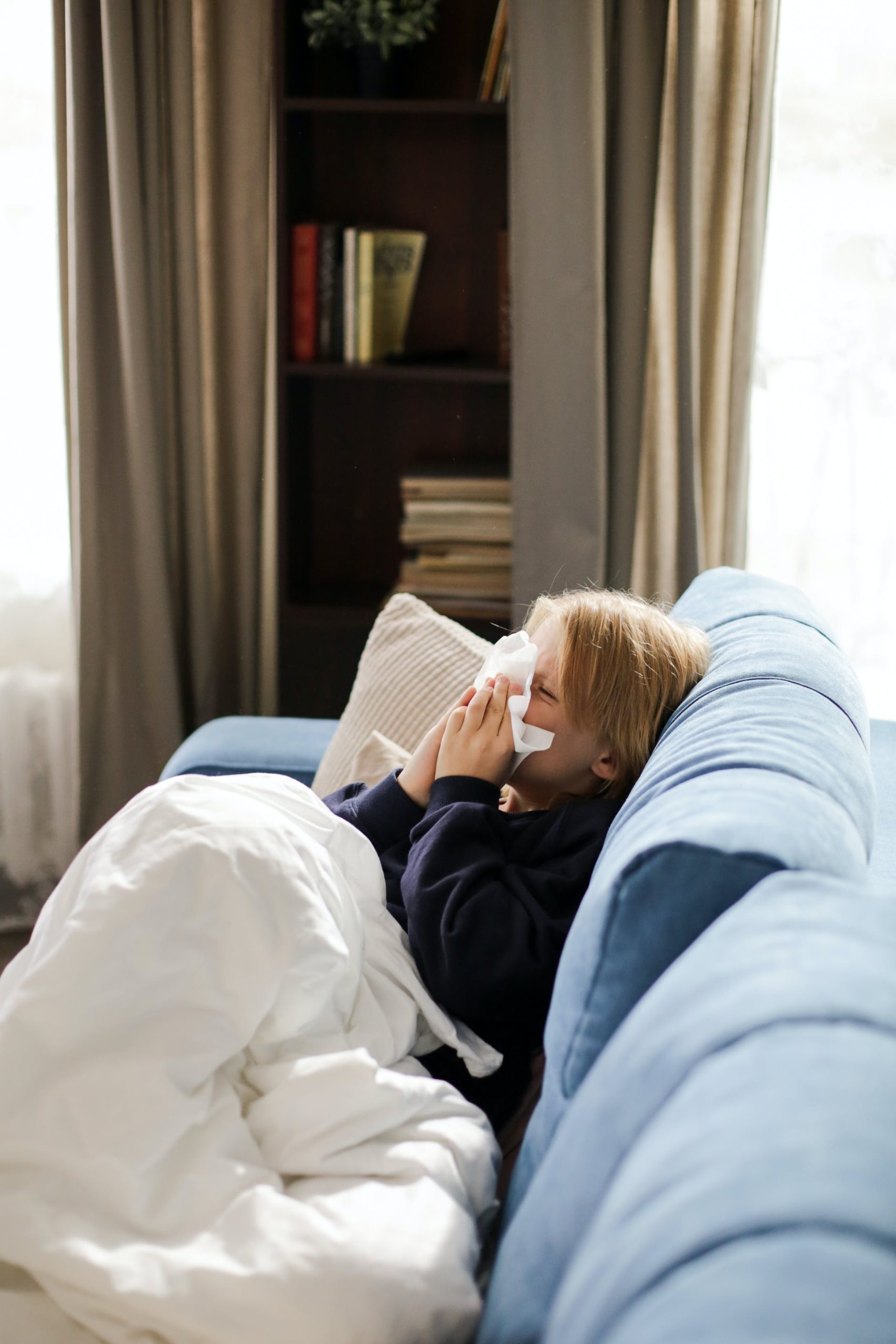 bronquiolitis, niño enfermo tumbado en el sofá sonándose la nariz